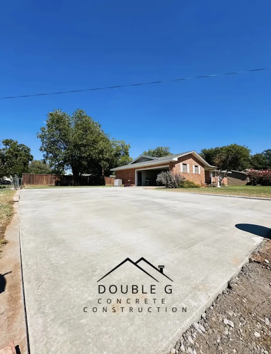 New concrete parking pad beside a brick home by Double G Concrete Construction